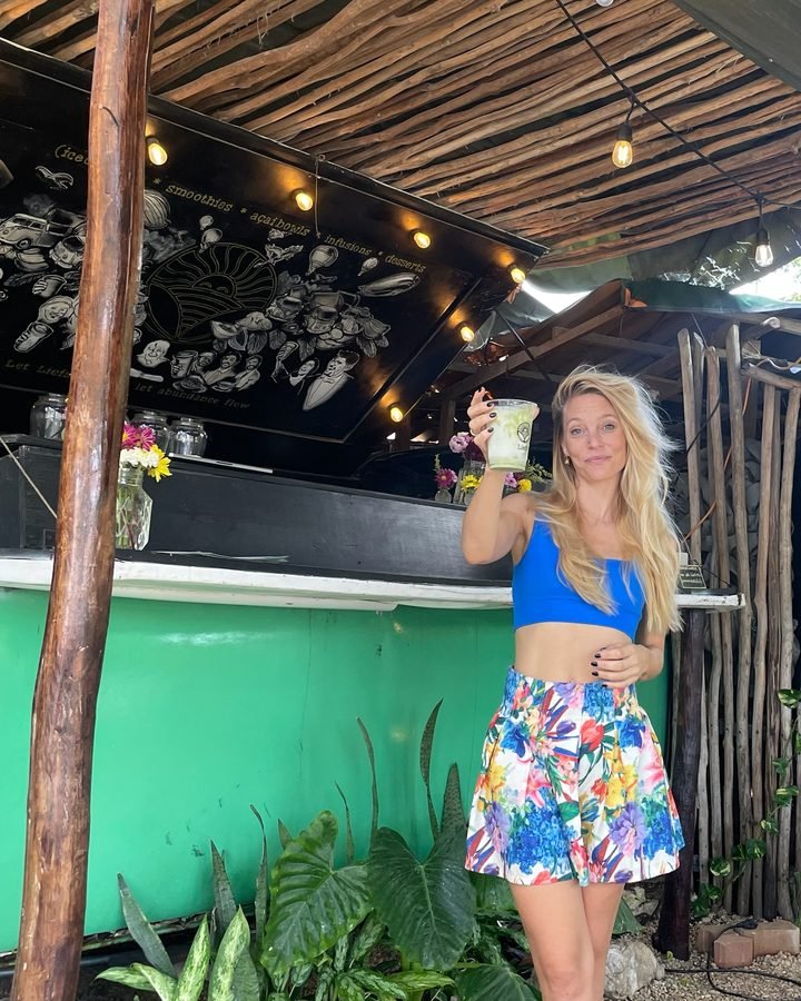 Fem, Liefs co-founder, in a blue top and floral skirt in front of the green VW Kombi at Liefs Tulum